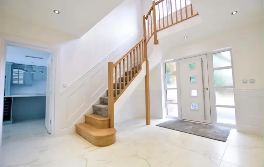 Bright entrance hall with timber staircase and wall panelling
